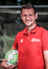 Kevin Dörr von der Per Mertesacker Stiftung, Rotes Shirt, Ball in der Hand, Fußballtor im Hintergrund